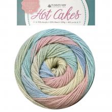 A multicolor skein of variegated yarn in pastel shades of pink, blue, green, and cream, shown below a circular product label that reads 'Hot Cakes' by the brand Fair Isle Yarn.