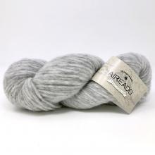 A skein of light gray marled yarn with a beige paper label wrapped around it, photographed on a clean white background.