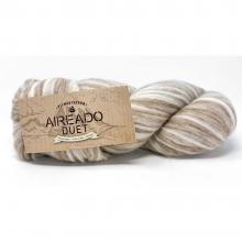 A skein of Aireado Duet yarn with a natural kraft paper label, showing variegated cream, beige, and light brown stripes, set against a plain white background.