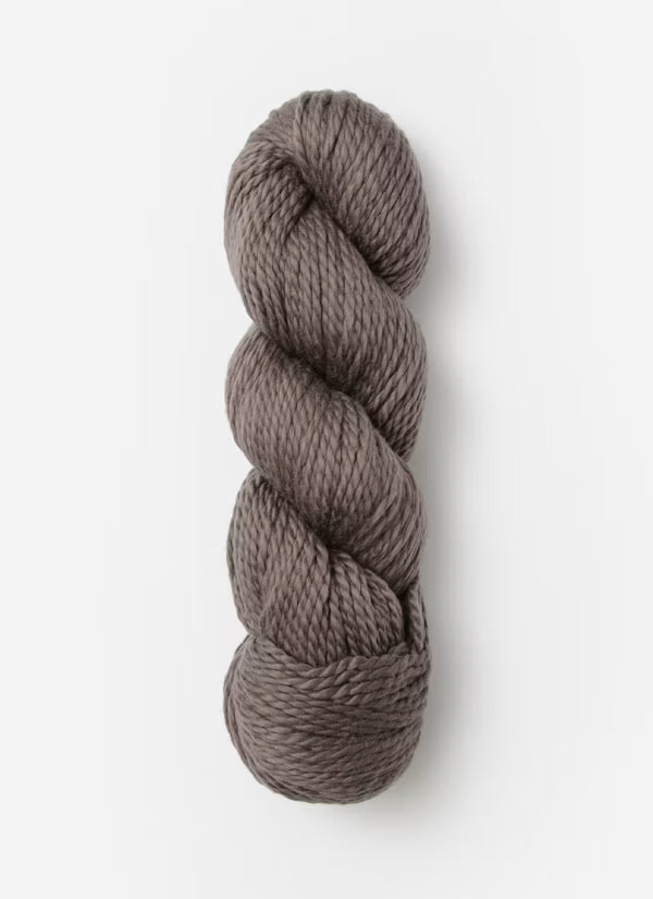 A single skein of twisted yarn in a warm taupe-brown color, photographed vertically against a clean white background.