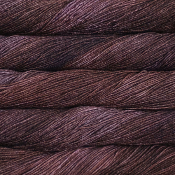 A close-up of tightly wound yarn skeins in a deep plum-brown color, filling the entire frame.