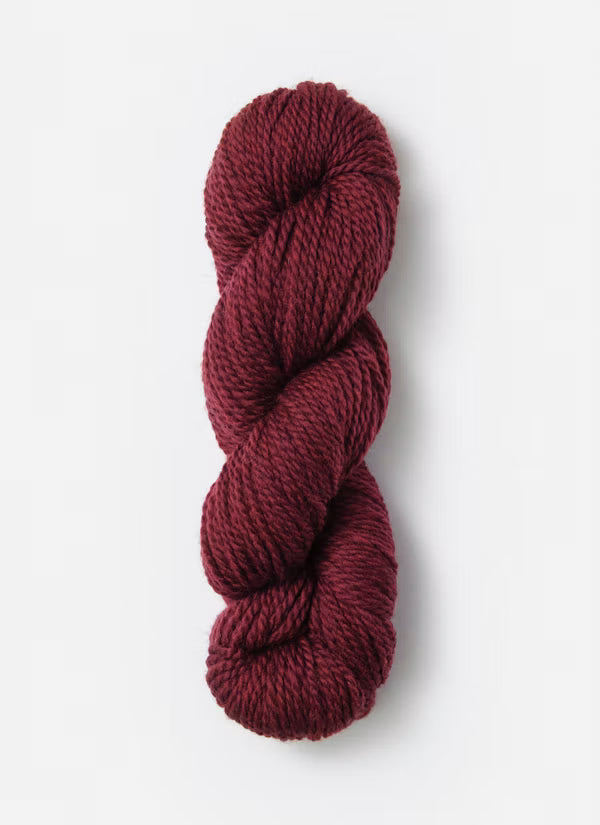 A single skein of twisted yarn in a deep burgundy red color, photographed vertically against a clean white background.