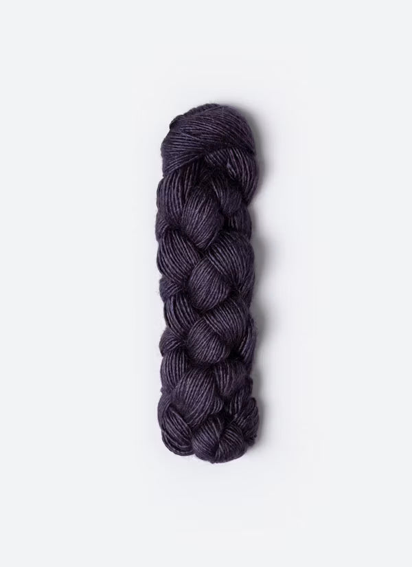 A single braided skein of yarn in a deep plum purple color, photographed vertically against a clean, light gray background.