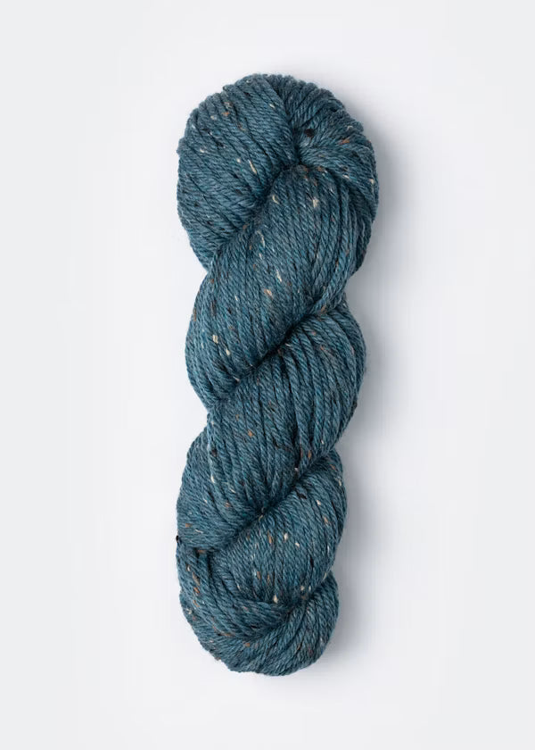A single skein of textured yarn in a heathered teal blue color with subtle flecks of white and brown, photographed on a clean white background.