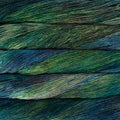 Close-up of variegated yarn strands in horizontal layers, showing a blend of deep green, teal, blue, and hints of yellow.