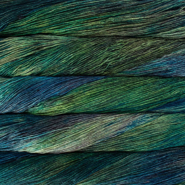 Close-up of variegated yarn strands in horizontal layers, showing a blend of deep green, teal, blue, and hints of yellow.