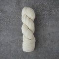 Single skein of cream-colored yarn on a gray textured background