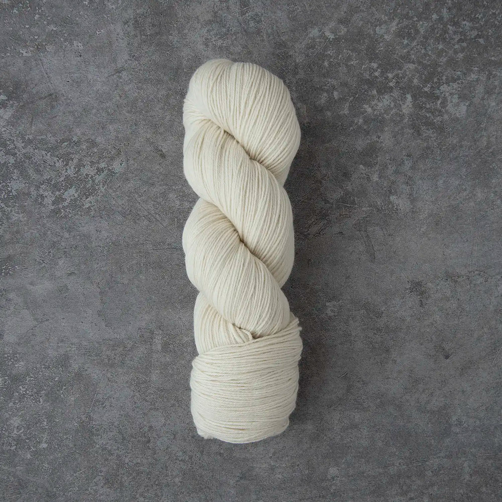 Single skein of cream-colored yarn on a gray textured background
