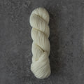 A skein of cream-colored yarn twisted into a hank, displayed vertically on a textured dark gray surface.