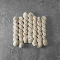 Set of six skeins of cream-colored yarn on a gray surface