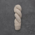 A single skein of cream-colored yarn twisted into a hank, displayed vertically on a textured dark gray slate surface.