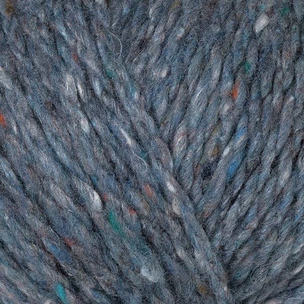 Close-up of variegated yarn with a heathered slate blue-gray base and small flecks of teal, orange, white, and brown.