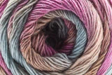 A close-up of a wound skein of variegated yarn with colors of dusty pink, lavender, teal, and dark brown.