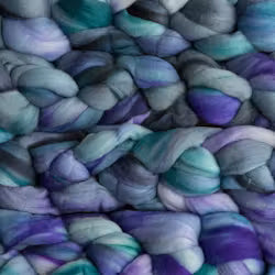 A close-up of chunky variegated yarn with blended shades of purple, teal, blue, and gray.