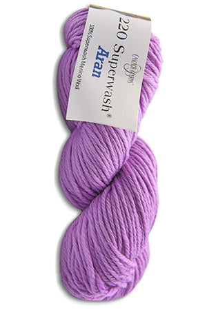 A skein of lavender purple yarn with a white paper label that reads '220 Superwash Aran' and 'Lion King', shown on a plain white background.