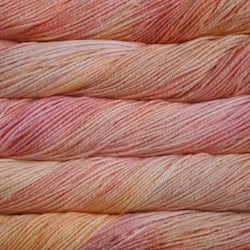 Close-up of twisted yarn skeins in a soft variegated blend of dusty pink, peach, and pale cream.