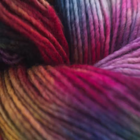 Close-up of variegated yarn with a rainbow colorway, showing transitions from yellow and orange to red, pink, purple, and blue.