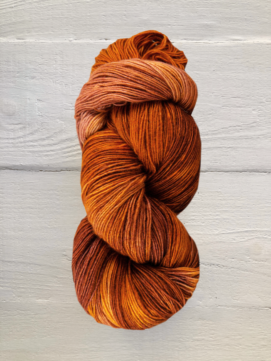 Skein of orange and brown yarn on a light wooden surface