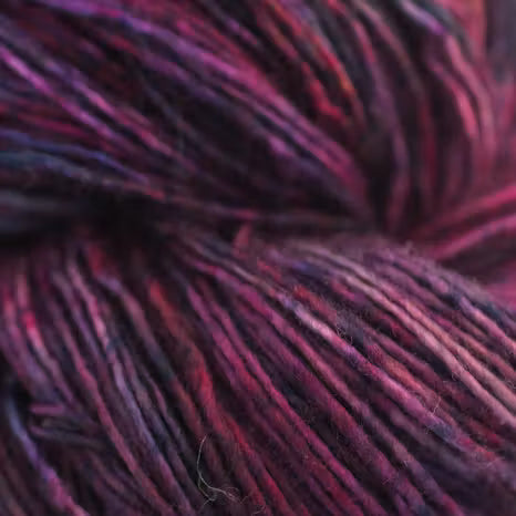 Close-up of variegated yarn with blended deep purple, burgundy, and dark maroon tones.