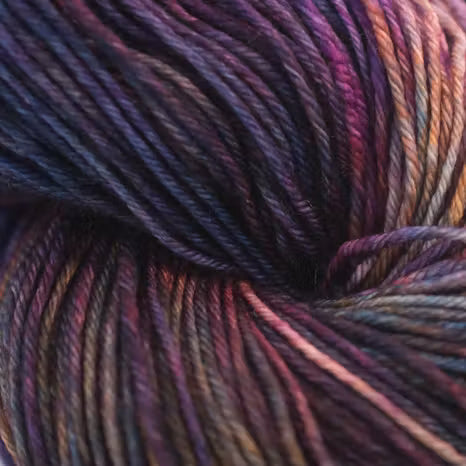 Close-up of variegated yarn with blended purple, pink, blue, and warm brown tones, filling the frame.