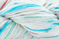 Close-up of a twisted yarn skein with white as the dominant color and fine stripes of light blue, light pink, and light green.