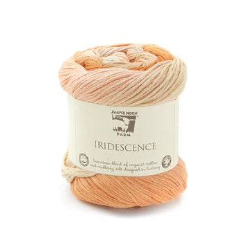 A skein of yarn from Nature's Own Fawn, named 'Iridescent', featuring a variegated color palette of peach, orange, and cream. The yarn is wrapped in a white paper label with black text and logo, set against a plain white background.