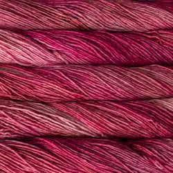 Close-up of variegated yarn strands in shades of deep pink, magenta, burgundy, and burgundy-red.
