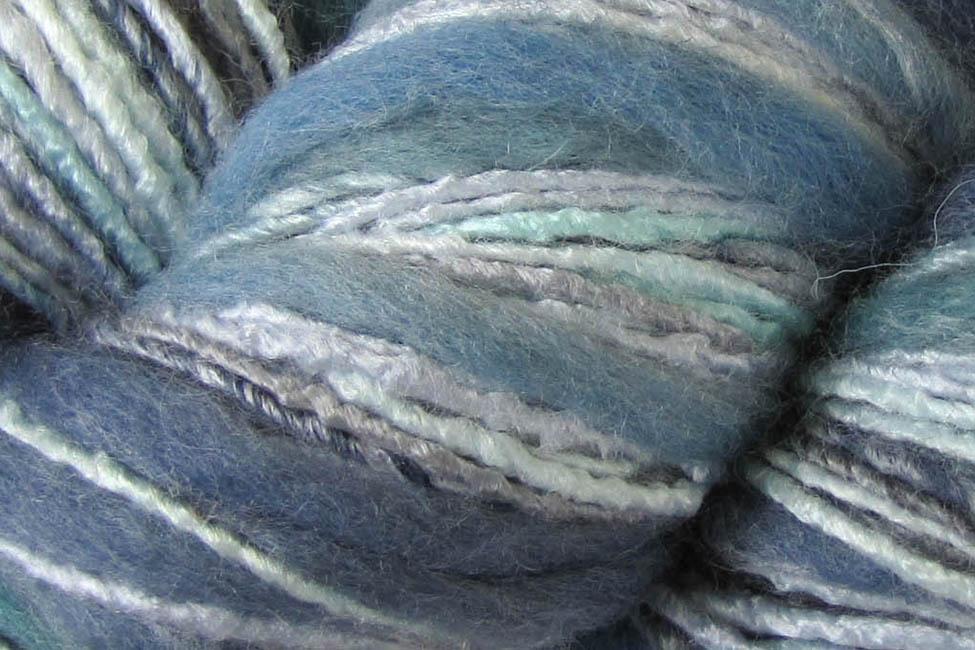 Close-up of variegated yarn with blended shades of dusty blue, teal, sage green, and off-white.
