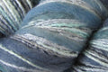 Close-up of variegated yarn with blended shades of dusty blue, teal, sage green, and off-white.