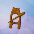 Wooden owl-shaped clip with a stick on a light blue background