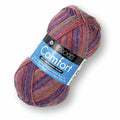 A skein of B&O BOCO Comfort knitting yarn in a variegated blend of purple, pink, and green, with a blue and black paper label, on a white background.