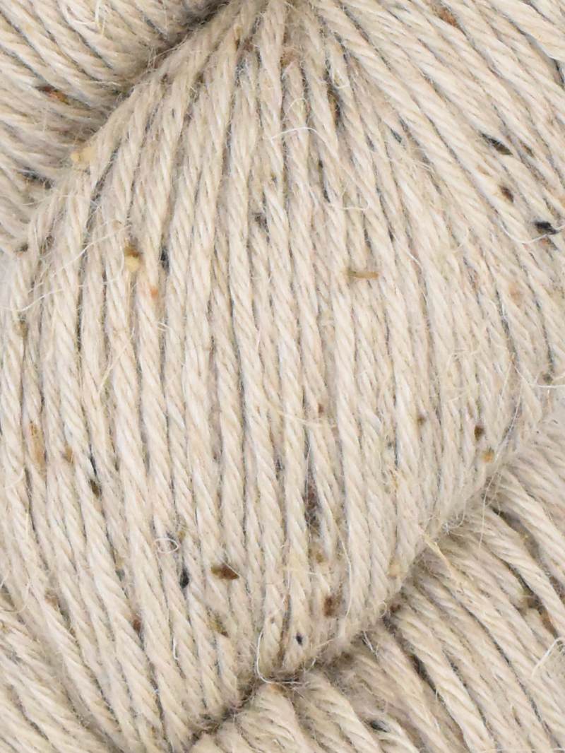 Close-up of a skein of chunky yarn in a warm oatmeal beige color, featuring small dark brown and black flecks throughout the plied texture.