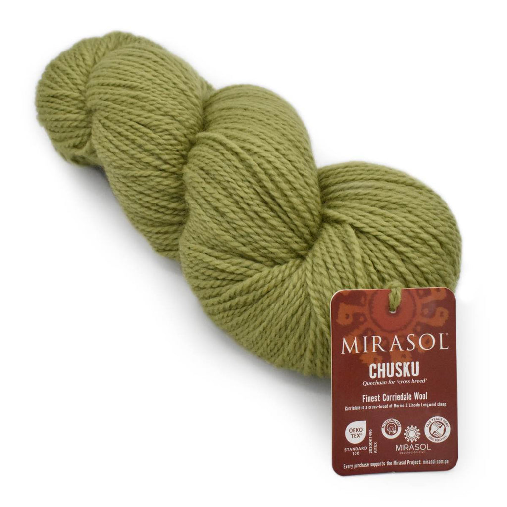 A skein of Mirasol Chusku wool yarn in a muted olive green color, shown with its brown paper product tag on a plain white background.