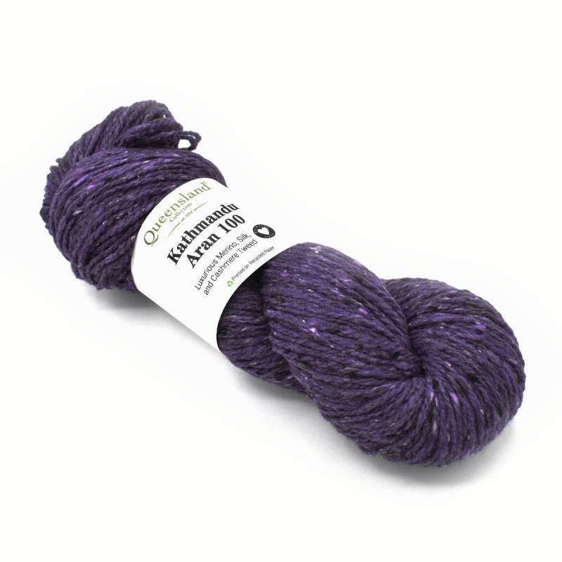 A skein of purple variegated yarn with a white paper label reading 'Queensland Yarns Kathmandu Aran 100', photographed on a clean white background.