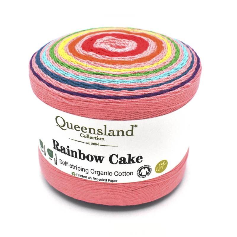 A single skein of Queensland Collection Rainbow Cake self-striping organic cotton yarn, showing its colorful spiral stripes and a white paper label, on a white background.
