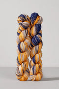 Two skeins of multicolored yarn on a light gray background