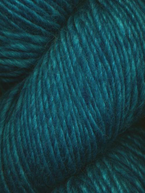 A close-up of teal blue yarn with a soft, slightly fuzzy texture, filling the entire frame.