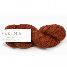 A skein of Yakima Coos Mountain Yarn in a warm rust-brown color, with a white paper label showing the brand name 'YAKIMA' on a clean white background.