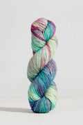 A single twisted hank of variegated yarn standing upright on a light gray studio background. The yarn shows blended pastel and bright tones including mint green, aqua, teal, blue, purple, pink, and cream.