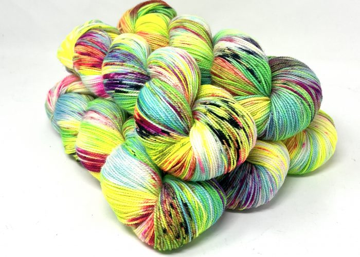 A pile of variegated yarn skeins in bright neon yellow, green, blue, pink, purple, and black on a plain white background.