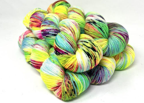 A pile of variegated yarn skeins in bright neon yellow, green, blue, pink, purple, and black on a plain white background.