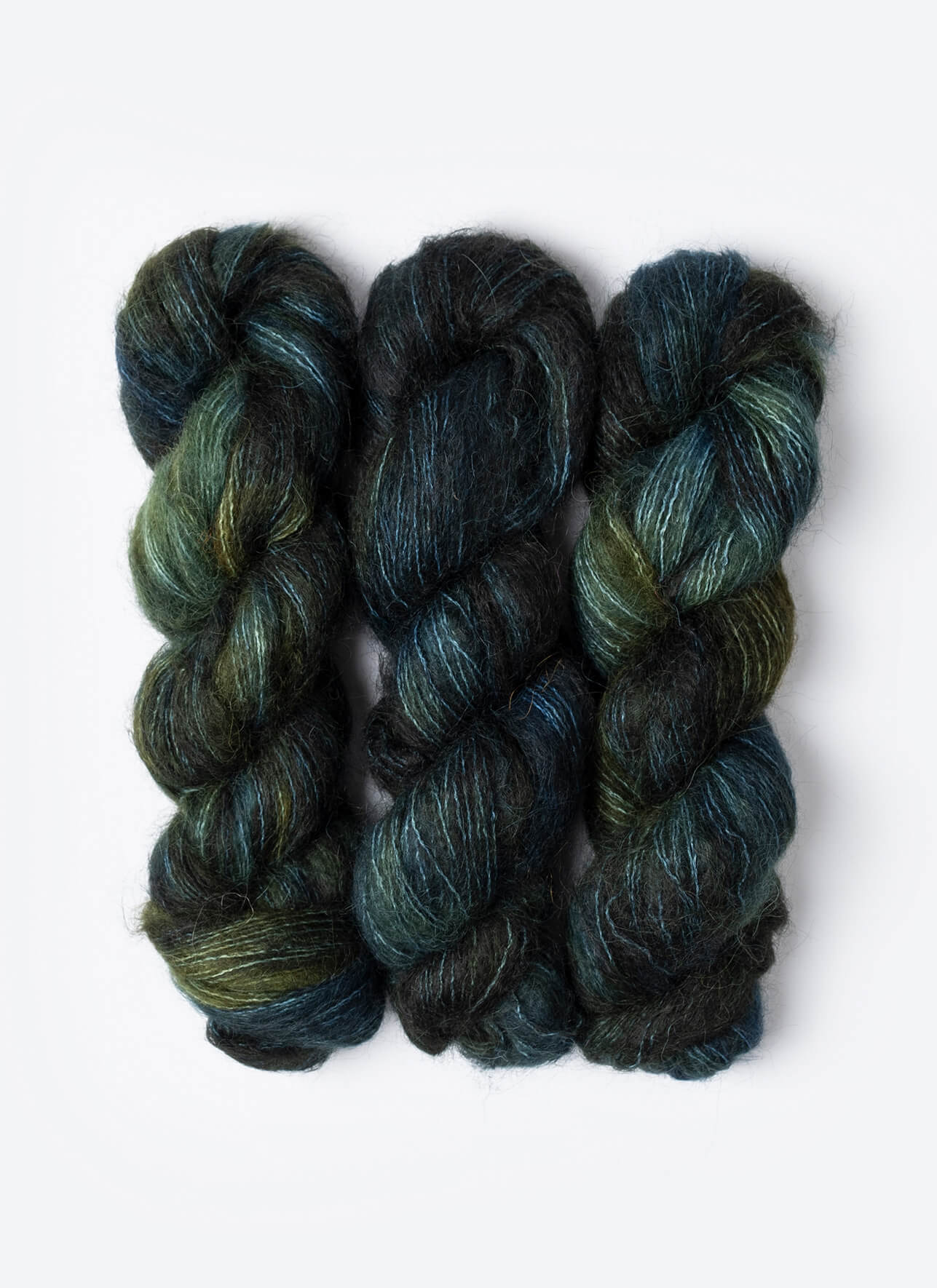 Three skeins of dark blue and green yarn on a white background