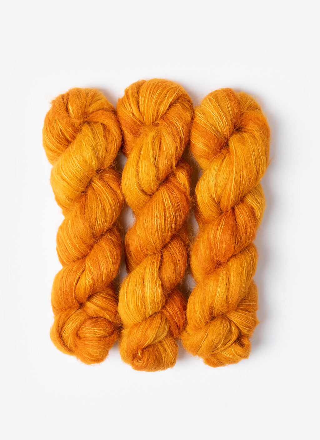 Three skeins of orange yarn on a white background