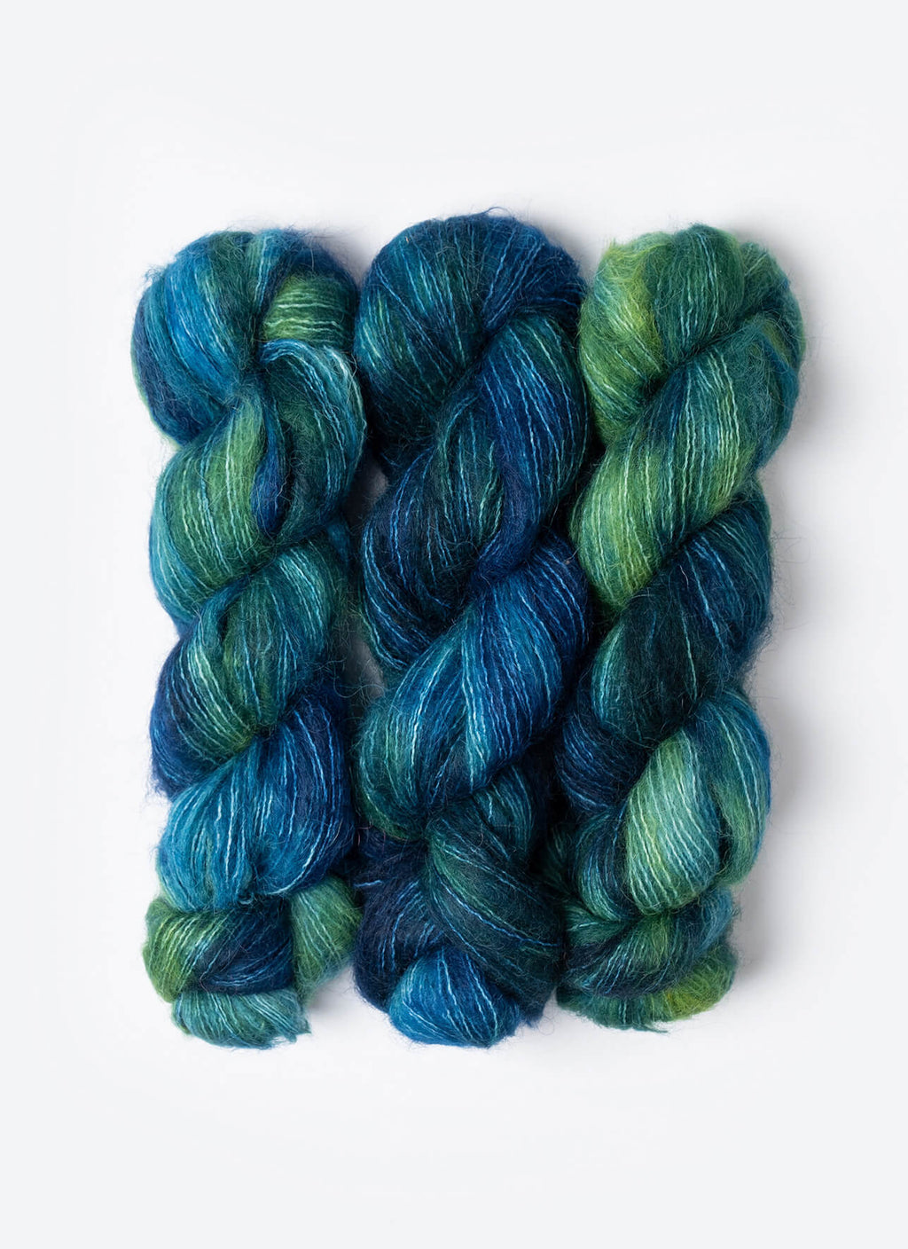 Three skeins of blue and green yarn on a white background