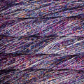 A close-up of textured yarn strands in a heathered, multicolored blend of purple, pink, blue, and white.