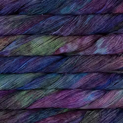 Close-up of twisted yarn strands stacked horizontally, showing a variegated color mix of purple, blue, green, and pink.