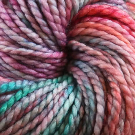 Close-up of variegated yarn with blended pink, coral, teal, and gray tones twisted into plies.