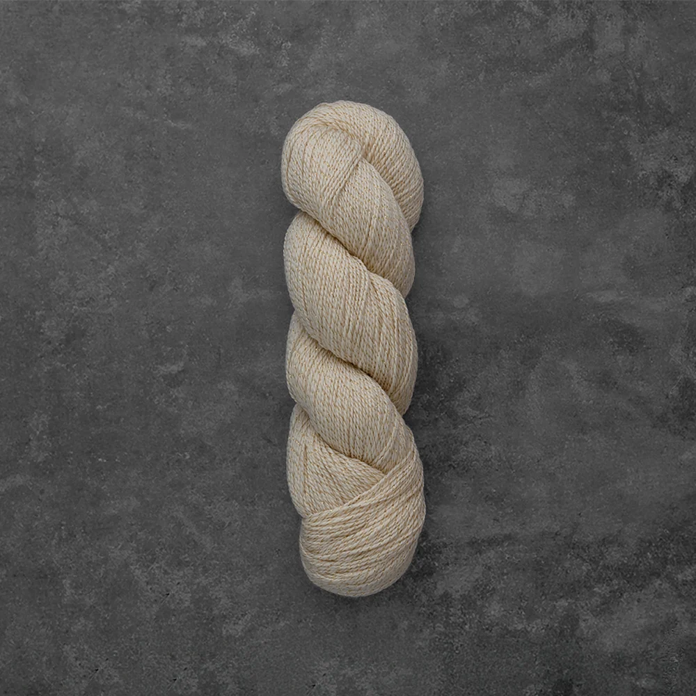 A single skein of cream-colored yarn twisted into a hank, displayed vertically against a dark textured gray background.