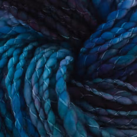 A close-up of braided yarn or cord in deep blue, teal, and purple tones, filling the entire frame.