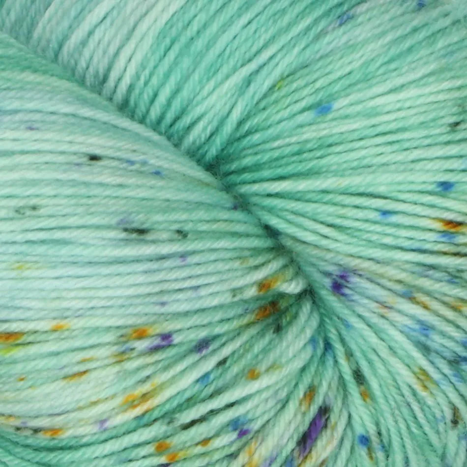 Close-up of speckled yarn in a light green color with small colorful specks.